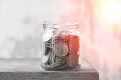 Muntstukken in een glaskruik tegen, besparingenmuntstukken - Investering en het concept van het de besparingsgeld van het Renteco stock fotografie Muntstukken in een glaskruik tegen, besparingenmuntstukken - Investering en het concept van het de besparingsgeld van het Renteco stock fotografie