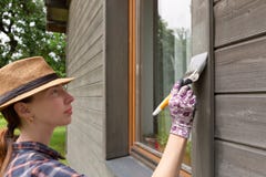 Mur extérieur de maison en bois de peinture de travailleuse avec le pinceau et la couleur protectrice en bois images libres de droits Mur extérieur de maison en bois de peinture de travailleuse avec le pinceau et la couleur protectrice en bois images libres de droits