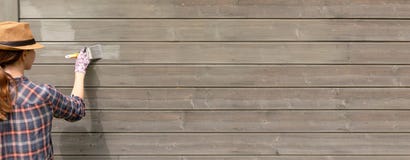 Mur extérieur de maison en bois de peinture de travailleuse avec le pinceau et la couleur protectrice en bois image libre de droits Mur extérieur de maison en bois de peinture de travailleuse avec le pinceau et la couleur protectrice en bois image libre de droits