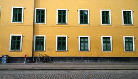 Murez la maison jaune lumineuse avec un bon nombre de beau Windows Au mur se penchant le vélo Près d'un petit courrier photos libres de droits Murez la maison jaune lumineuse avec un bon nombre de beau Windows Au mur se penchant le vélo Près d'un petit courrier photos libres de droits