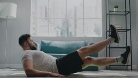 Muscular athlete with beard practices flutter kicks exercise