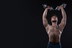 Muscular bodybuilder guy doing exercises with dumbbells over black background royalty free stock photography Muscular bodybuilder guy doing exercises with dumbbells over black background royalty free stock photography