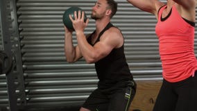 Muscular couple doing ball exercise