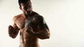 Muscular shirtless bodybuilder flexing in studio