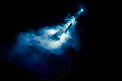 Music concept. Acoustic guitar isolated on a dark background under beam of light with smoke with copy space. Guitar Strings, close