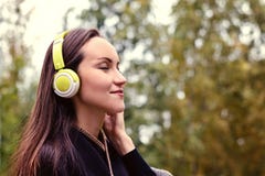 Musica d'ascolto della giovane donna felice dallo smartphone con le cuffie in un parco calmo fotografia stock Musica d'ascolto della giovane donna felice dallo smartphone con le cuffie in un parco calmo fotografia stock