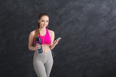 Musica d'ascolto della ragazza felice di forma fisica sullo smartphone e sull'acqua potabile immagini stock libere da diritti Musica d'ascolto della ragazza felice di forma fisica sullo smartphone e sull'acqua potabile immagini stock libere da diritti