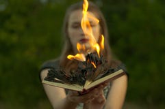 Musica di notte La ragazza tiene un libro bruciante contro lo sfondo della foresta fotografie stock Musica di notte La ragazza tiene un libro bruciante contro lo sfondo della foresta fotografie stock
