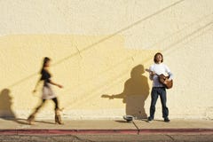 Musician On Sidewalk And Woman Pedestrian Royalty Free Stock Photography Musician On Sidewalk And Woman Pedestrian Royalty Free Stock Photography