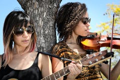 Musiciens de femmes jouant la guitare et le violon dehors image libre de droits Musiciens de femmes jouant la guitare et le violon dehors image libre de droits
