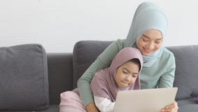 Muslim mother woman playing laptop computer at home with her child