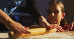 Mutter rollt den Teig und die unterrichtende Tochter, um zu kochen stock footage Mutter rollt den Teig und die unterrichtende Tochter, um zu kochen stock footage