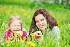 Mutter und Tochter, die Äpfel auf grüner Sommerwiese essen lizenzfreies stockbild Mutter und Tochter, die Äpfel auf grüner Sommerwiese essen lizenzfreies stockbild