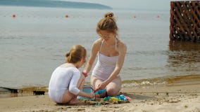 Mutter und Tochter spielen auf dem Strand und errichten ein Sandburg Sonniger Tag des Sommers ferien stock video Mutter und Tochter spielen auf dem Strand und errichten ein Sandburg Sonniger Tag des Sommers ferien stock video