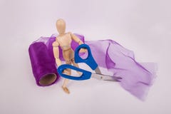 Muñeca articulada de madera del maniquí que lleva a cabo el rollo púrpura de la tela de Tulle de las tijeras en fondo fotos de archivo Muñeca articulada de madera del maniquí que lleva a cabo el rollo púrpura de la tela de Tulle de las tijeras en fondo fotos de archivo