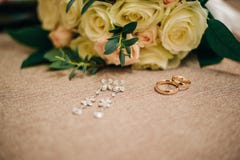Mycket härlig bröllopbukett från vita rosor med guld- vigselringar och dyrbara örhängen Royaltyfri Foto Mycket härlig bröllopbukett från vita rosor med guld- vigselringar och dyrbara örhängen Royaltyfri Foto
