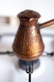 Mycket varm klar kaffehatt - kaffe som bryggas i en kopparcezve på en gasugn i hemtrevligt typisk kök i morgonen royaltyfri bild Mycket varm klar kaffehatt - kaffe som bryggas i en kopparcezve på en gasugn i hemtrevligt typisk kök i morgonen royaltyfri bild