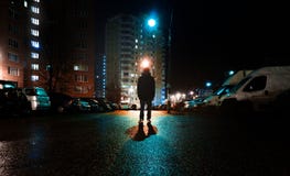 A mysterious man stands alone in the street, among cars in an empty city, weat road after the rain, walks the night street, dreams Royalty Free Stock Images A mysterious man stands alone in the street, among cars in an empty city, weat road after the rain, walks the night street, dreams Royalty Free Stock Images