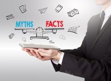Myths vs facts Balance, young man holding a tablet computer royalty free stock photography Myths vs facts Balance, young man holding a tablet computer royalty free stock photography