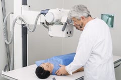 Máquina de radiografía masculina del doctor Adjusting sobre paciente en hospital imagen de archivo Máquina de radiografía masculina del doctor Adjusting sobre paciente en hospital imagen de archivo
