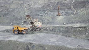 Máquina escavadora e caminhão basculante ao carregar o minério de pedra em uma pedreira cinzenta, setor mineiro estoque Cargas de fotografia de stock Máquina escavadora e caminhão basculante ao carregar o minério de pedra em uma pedreira cinzenta, setor mineiro estoque Cargas de fotografia de stock