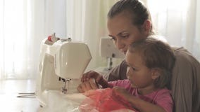 Mãe atrativa nova que trabalha na máquina de costura com sua filha bonito pequena filme Mãe atrativa nova que trabalha na máquina de costura com sua filha bonito pequena filme