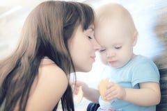 A mãe bonita que joga com sua criança bonita, a criança come a cookie e os risos imagens de stock royalty free A mãe bonita que joga com sua criança bonita, a criança come a cookie e os risos imagens de stock royalty free