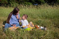 Mãe e filho novo que comem em uma barraca do ar livre do piquenique foto de stock Mãe e filho novo que comem em uma barraca do ar livre do piquenique foto de stock