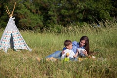 Mãe e filho novo que comem em uma barraca do ar livre do piquenique imagens de stock Mãe e filho novo que comem em uma barraca do ar livre do piquenique imagens de stock