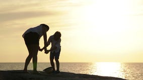 A mãe e o filho ficam no afloramento que negligencia o mar no por do sol e no riso video estoque A mãe e o filho ficam no afloramento que negligencia o mar no por do sol e no riso video estoque