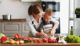 Mãe feliz da família com o filho da criança que prepara a salada vegetal imagens de stock royalty free Mãe feliz da família com o filho da criança que prepara a salada vegetal imagens de stock royalty free