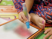 Mão asiática pequena do ` s do bebê que guarda a pena grande da cor para fazer a pintura fotos de stock Mão asiática pequena do ` s do bebê que guarda a pena grande da cor para fazer a pintura fotos de stock
