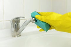 A mão de um homem que faz a limpeza limpa um torneira com água foto de stock royalty free A mão de um homem que faz a limpeza limpa um torneira com água foto de stock royalty free
