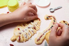A mão de uma criança faz cookies do Natal da massa sob a forma de uma árvore de Natal Preparando-se para o Natal, uma família coz foto de stock royalty free A mão de uma criança faz cookies do Natal da massa sob a forma de uma árvore de Natal Preparando-se para o Natal, uma família coz foto de stock royalty free