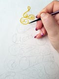 A mão fêmea do artista começou a pintar em uma aquarela de uma árvore de Natal da cor amarela com uma inscrição de fotografia de stock A mão fêmea do artista começou a pintar em uma aquarela de uma árvore de Natal da cor amarela com uma inscrição de fotografia de stock