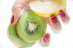 Mão fêmea que guarda uma fatia de frutos frescos sob a água fotos de stock Mão fêmea que guarda uma fatia de frutos frescos sob a água fotos de stock