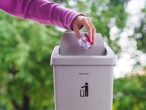 Mão fêmea que trowing um papel em um escaninho de lixo no backgrou do bokeh Imagens de Stock Mão fêmea que trowing um papel em um escaninho de lixo no backgrou do bokeh Imagens de Stock