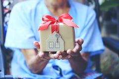 Mãos do homem superior que guardam a caixa de presente com modelo vermelho da fita e da casa com chaves, a casa nova do presente imagens de stock Mãos do homem superior que guardam a caixa de presente com modelo vermelho da fita e da casa com chaves, a casa nova do presente imagens de stock