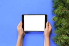 Mãos fêmeas com o tablet pc no fundo roxo do Natal Opinião superior de ramo de árvore do Xmas foto de stock royalty free Mãos fêmeas com o tablet pc no fundo roxo do Natal Opinião superior de ramo de árvore do Xmas foto de stock royalty free