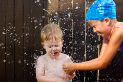 Mädchen, das eine Wasserbombe auf kleinem Bruder bricht lizenzfreie stockfotos Mädchen, das eine Wasserbombe auf kleinem Bruder bricht lizenzfreie stockfotos