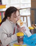 Mädchen, das einen Hotdog in einem Café isst stockbild Mädchen, das einen Hotdog in einem Café isst stockbild