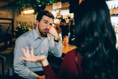 Mädchen, das vor jungem Kerl sitzt und mit ihm spricht Er schaut gebohrt Mann ist nicht am Gespräch an allen interessiert stockfotografie Mädchen, das vor jungem Kerl sitzt und mit ihm spricht Er schaut gebohrt Mann ist nicht am Gespräch an allen interessiert stockfotografie