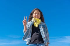 M?dchen mit dem schwarzen langen Haar gegen das klare l?chelnde Schauen des blauen Himmels zur Kamera, welche die Finger tun Sieg lizenzfreies stockfoto M?dchen mit dem schwarzen langen Haar gegen das klare l?chelnde Schauen des blauen Himmels zur Kamera, welche die Finger tun Sieg lizenzfreies stockfoto