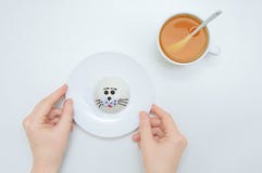 Mädchen am Tisch hält eine weiße Platte mit Kuchen In der Nähe gibt es eine Schale mit grünem Tee lizenzfreie stockfotografie Mädchen am Tisch hält eine weiße Platte mit Kuchen In der Nähe gibt es eine Schale mit grünem Tee lizenzfreie stockfotografie