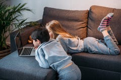 Mädchen und Junge, der Laptop verwendet und auf Sofa liegt Stockbild Mädchen und Junge, der Laptop verwendet und auf Sofa liegt Stockbild