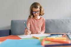 Mädchen von 8 Jahren, die zu Hause auf dem Sofa zeichnet Schreiben mit Bleistift im Notizbuch sitzen Kinderblondine mit Gläsern z lizenzfreie stockbilder Mädchen von 8 Jahren, die zu Hause auf dem Sofa zeichnet Schreiben mit Bleistift im Notizbuch sitzen Kinderblondine mit Gläsern z lizenzfreie stockbilder