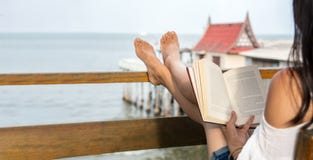 Mädchenlesebuch auf dem Balkon mit Küstenansicht stockfotografie Mädchenlesebuch auf dem Balkon mit Küstenansicht stockfotografie