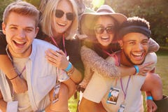 Män som ger kvinnaridturer på axlarna på deras väg till musikfestivalen arkivfoto Män som ger kvinnaridturer på axlarna på deras väg till musikfestivalen arkivfoto