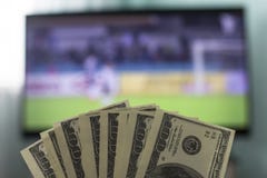 Männer ` s Hände halten Gelddollar vor dem hintergrund eines Fernsehers, auf dem Fußball spielt, Nahaufnahmen lizenzfreie stockfotografie Männer ` s Hände halten Gelddollar vor dem hintergrund eines Fernsehers, auf dem Fußball spielt, Nahaufnahmen lizenzfreie stockfotografie