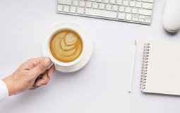 Männliche Hand, die Kaffeetasse Lattekunst auf weißer moderner Funktionstabelle hält stockbild Männliche Hand, die Kaffeetasse Lattekunst auf weißer moderner Funktionstabelle hält stockbild
